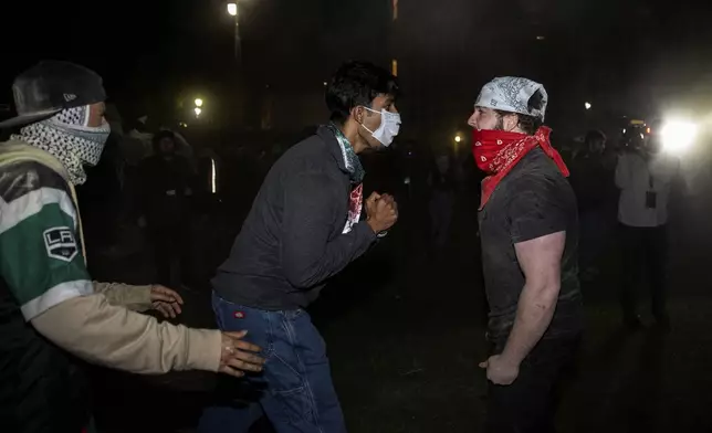 Demonstrators clash at a pro-Palestinian encampment at UCLA Tuesday, April 30, 2024, in Los Angeles. Dueling groups of protesters have clashed at the University of California, Los Angeles, grappling in fistfights and shoving, kicking and using sticks to beat one another. (AP Photo/Ethan Swope)