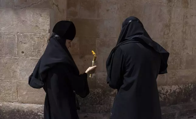 Greek Orthodox nuns hold candles as they gather during the ceremony of the Holy Fire at the Church of the Holy Sepulchre, where many Christians believe Jesus was crucified, buried and rose from the dead, in the Old City of Jerusalem, Saturday, May 4, 2024. (AP Photo/Ohad Zwigenberg)