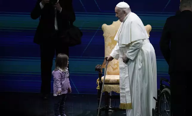 Pope Francis speaks with a young girl as he arrives for an annual gathering of pro-family organisations at the Auditorium della Conciliazione, in Rome, Friday, May 10, 2024. (AP Photo/Alessandra Tarantino)