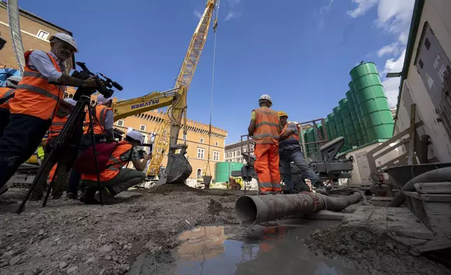 International journalists scan the construction site of the new 25.5-kilometer Metro C subway main hub in Piazza Venezia in central Rome, Thursday, May 23, 2024. During a tour Thursday of the construction site at Piazza Venezia, chief engineer Andrea Sciotti said works on the nearly 3 billion euro project, considered one of the most complicated in the world, were running at pace to be completed by 2034. (AP Photo/Domenico Stinellis)