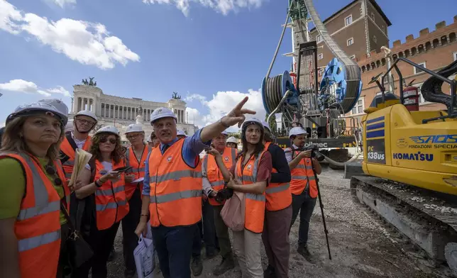 Chief engineer Andrea Sciotti, center, technical director for Rome's new 25.5-kilometer Metro C subway talks to international journalists at the construction site of line C main hub in central Rome, Thursday, May 23, 2024. During a tour Thursday of the construction site at Piazza Venezia, Sciotti said works on the nearly 3 billion euro project, considered one of the most complicated in the world, were running at pace to be completed by 2034. In the background the Unknown Soldier monument. (AP Photo/Domenico Stinellis)