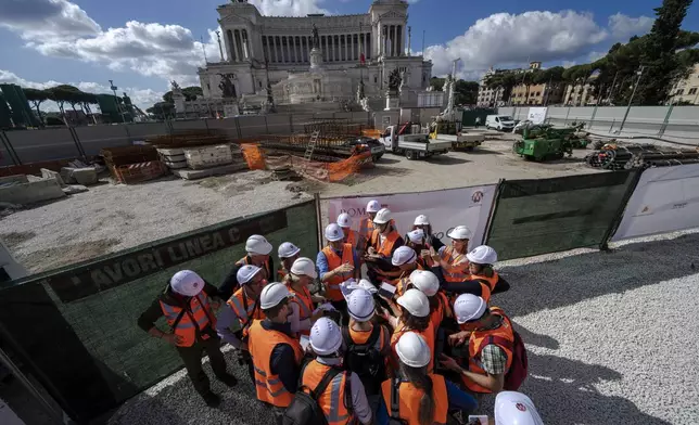 Chief engineer Andrea Sciotti, center, technical director for Rome's new 25.5-kilometer Metro C subway talks to international journalists at the construction site of line C main hub in central Rome, Thursday, May 23, 2024. During a tour Thursday of the construction site at Piazza Venezia, Sciotti said works on the nearly 3 billion euro project, considered one of the most complicated in the world, were running at pace to be completed by 2034. In the background the Unknown Soldier monument. (AP Photo/Domenico Stinellis)