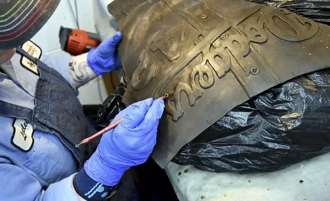 An employee at Art Castings of Colorado touches up a wax mold of Jackie Robinson's jersey in Loveland, Colo. on Wednesday, May 8, 2024. The original statue was cut off at the ankles and stolen from a park in Wichita, Kansas in January. The Colorado foundry cast that sculpture in 2019 and, luckily, still had the original plaster and rubber molds. (AP Photo/Thomas Peipert)