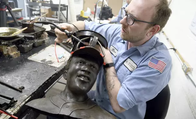 David Hobbs, an employee at Art Castings of Colorado, touches up a wax mold of Jackie Robinson's head in Loveland, Colo. on Wednesday, May 8, 2024. The original statue was cut off at the ankles and stolen from a park in Wichita, Kansas in January. The Colorado foundry cast that sculpture in 2019 and, luckily, still had the original plaster and rubber molds. (AP Photo/Thomas Peipert)