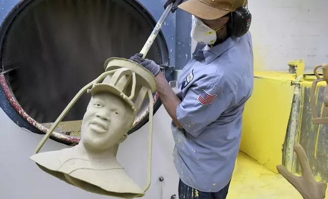 Jesse Justus, an employee at Art Castings of Colorado, touches up a wax mold of Jackie Robinson's head in Loveland, Colo. on Wednesday, May 8, 2024. The original statue was cut off at the ankles and stolen from a park in Wichita, Kansas in January. The Colorado foundry cast that sculpture in 2019 and, luckily, still had the original plaster and rubber molds. (AP Photo/Thomas Peipert)