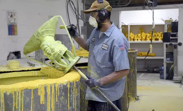 Jesse Justus, an employee at Art Castings of Colorado, coats a mold of Jackie Robinson's head in Loveland, Colo. on Wednesday, May 8, 2024. The original statue was cut off at the ankles and stolen from a park in Wichita, Kansas in January. The Colorado foundry cast that sculpture in 2019 and, luckily, still had the original plaster and rubber molds. (AP Photo/Thomas Peipert)