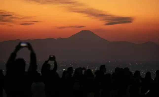 FILE- Visitors take pictures of Mount Fuji from Shibuya Sky observation deck Monday, Jan. 20, 2020, in the Shibuya district of Tokyo. (AP Photo/Jae C. Hong, File)