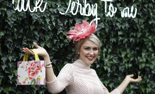 FILE - A woman wears a hat and poses for a picture during the 145th running of the Kentucky Derby horse race at Churchill Downs Saturday, May 4, 2019, in Louisville, Ky. The first Saturday in May is Derby Day with all its accompanying pageantry, including fancy hats. (AP Photo/Darron Cummings, File)