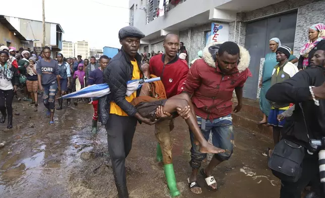 FILE - Residents rescue a woman who was caught during heavy rain in the Mathare area of Nairobi, Kenya, April 24, 2024. (AP Photo/Andrew Kasuku, File)