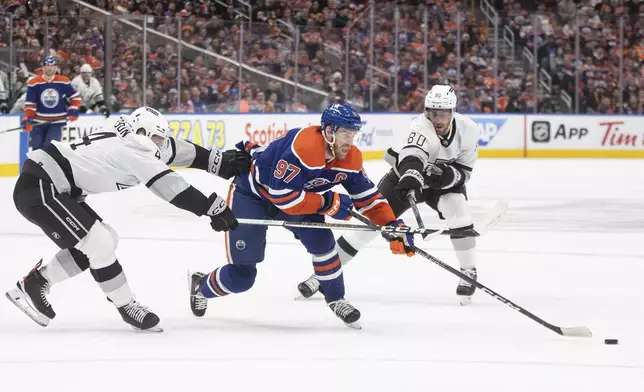 Los Angeles Kings' Mikey Anderson (44) and Pierre-Luc Dubois (80) chase Edmonton Oilers' Connor McDavid (97) during the second period in Game 5 of an NHL hockey Stanley Cup first-round playoff series, on Wednesday May 1, 2024, in Edmonton, Alberta. (Jason Franson/The Canadian Press via AP)