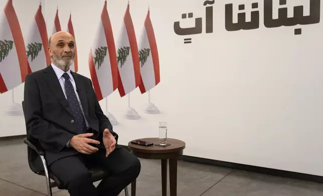 Samir Geagea, leader of the Christian Lebanese Forces party, speaks during an interview with the Associated Press, in Maarab east of Beirut, Tuesday, April 30, 2024. Geagea blasted the Shiite militant group Hezbollah for opening a front with Israel to back up its ally Hamas, saying it has harmed Lebanon without making a dent in Israel's crushing offensive in the Gaza Strip. The Arabic words on the wall read:"Our Lebanon is coming." (AP Photo/Hussein Malla)