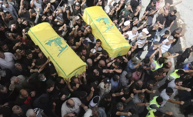 Mourners shout slogans as they carry the coffins of Hezbollah commanders Hussein Youssef Salleh and Rafik Hassan Qassem, who were killed by an Israeli strike, during their funeral procession in Aita al-Shaab village, south Lebanon, Monday, May 27, 2024. (AP Photo/Mohammad Zaatari)