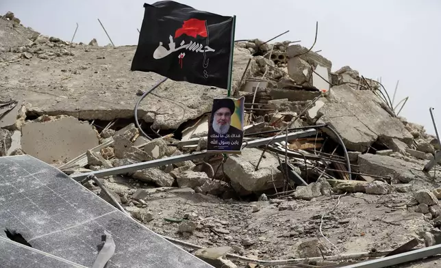 A picture of Hezbollah leader Sayyed Hassan Nasrallah sits on a house previously destroyed in an Israeli strike, in Aita al-Shaab village, south Lebanon, Monday, May 27, 2024. The Arabic on flag reads: "Oh Hussein." (AP Photo/Mohammad Zaatari)
