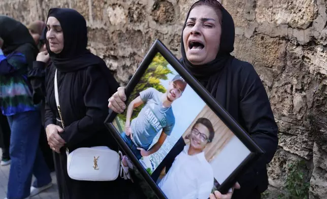 A Lebanese woman mourns, as she holds a frame with the portraits of two victims who were among four civilians from the same family that killed on Sunday by Israeli strikes on the southern town of Mays al-Jabal, during their funeral procession, in Beirut, Monday, May 6, 2024. Hezbollah militants and Israeli forces have been exchanging fire in south Lebanon since a day after the Israel-Hamas war began on Oct. 7. (AP Photo/Hussein Malla)