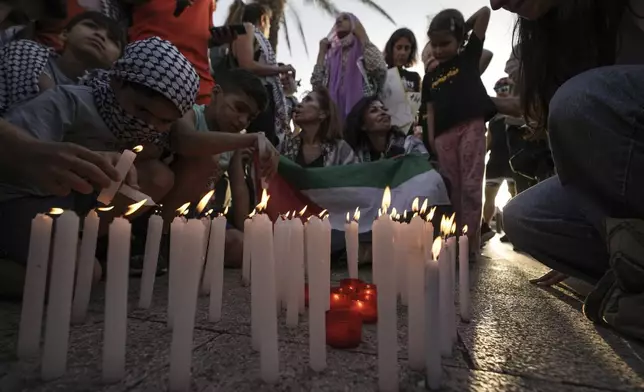 Children light candles during a march against Israel and in solidarity with Palestinians in the southern Gaza city of Rafah, on the Mediterranean Sea corniche in Beirut, Lebanon, Monday, May 27, 2024. Israeli Prime Minister Benjamin Netanyahu acknowledged Monday that a "tragic mistake" had been made after an Israeli strike in the southern Gaza city of Rafah set fire to a tent camp housing displaced Palestinians and killed at least 45 people, according to local officials. (AP Photo/Hassan Ammar)