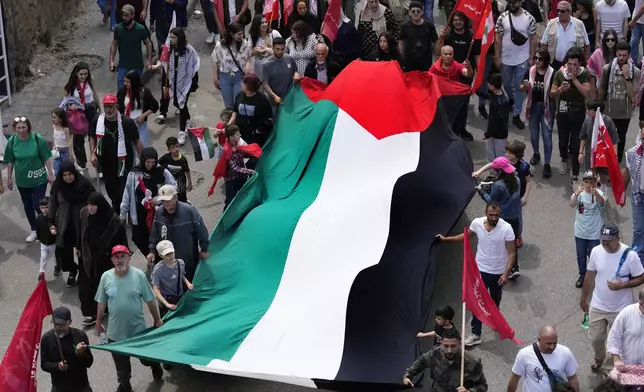 Supporters of the Lebanese Communist party, wave a giant Palestinian flag, as they march during a demonstration to mark International Labor Day or May Day, in Beirut, Wednesday, May 1, 2024. Despite the tense situation and ongoing clashes on Lebanon's border with Israel over the past seven months, hundreds of protesters marched through Beirut's streets. (AP Photo/Hussein Malla)