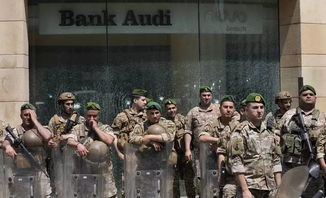 FILE - Lebanese soldiers stand guard in front Bank Audi branch which its windows smashed by angry depositors in downtown Beirut, Lebanon, Tuesday, May 9, 2023. Poverty in Lebanon tripled over the course of a decade during which the small Mediterranean country slid into a protracted financial crisis, the World Bank said Thursday, May 23, 2024. (AP Photo/Hussein Malla, File)