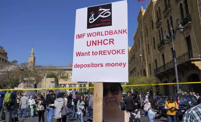FILE - A protesting depositor carries a placard at a protest near Parliament in downtown Beirut, Lebanon, Tuesday, May 9, 2023. Poverty in Lebanon tripled over the course of a decade during which the small Mediterranean country slid into a protracted financial crisis, the World Bank said Thursday, May 23, 2024. (AP Photo/Hussein Malla, File)