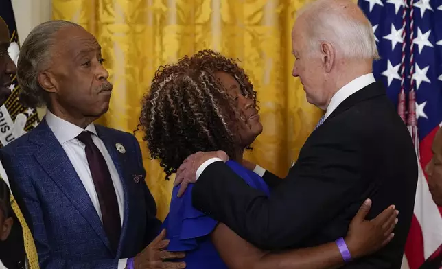 FILE - President Joe Biden hugs Tamika Palmer, mother of Breonna Taylor, as Rev. Al Sharpton watches after Biden signed an executive order in the East Room of the White House, Wednesday, May 25, 2022, in Washington. The order comes on the second anniversary of George Floyd's death, and is focused on policing. (AP Photo/Alex Brandon, File)