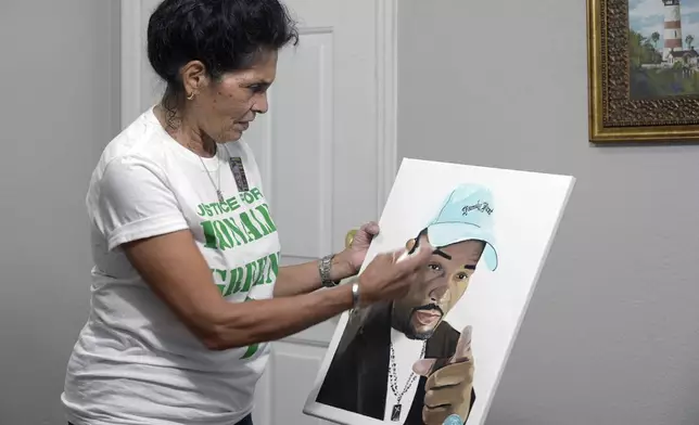 FILE - Mona Hardin recounts the events surrounding the death of her son, Ronald Greene, as she holds a painting of him in Orlando, Fla., on Saturday, Dec. 4, 2021. Hardin has been waiting five long years for any resolution to the federal investigation into her son’s deadly arrest by Louisiana State Police troopers, an anguish only compounded by the fact that nearly every other major civil rights case during that time has passed her by. (AP Photo/Phelan M. Ebenhack, File)