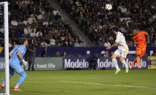 Houston Dynamo forward Latif Blessing, right, tries to scores as LA Galaxy midfielder Gastón Brugman, center, defends and goalkeeper John McCarthy stands in goal during the first half of a Major League Soccer match Saturday, May 25, 2024, in Carson, Calif. (AP Photo/Mark J. Terrill)
