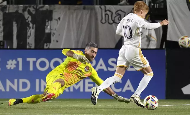 Houston Dynamo goalkeeper Andrew Tarbell, left, tries to stop LA Galaxy midfielder Riqui Puig during the first half of a Major League Soccer match Saturday, May 25, 2024, in Carson, Calif. (AP Photo/Mark J. Terrill)