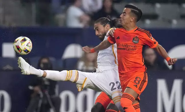 LA Galaxy defender Martín Cáceres, left, kicks while under pressure from Houston Dynamo midfielder Amine Bassi during the first half of a Major League Soccer match Saturday, May 25, 2024, in Carson, Calif. (AP Photo/Mark J. Terrill)