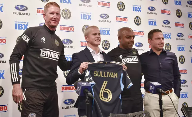 Philadelphia Union manager Jim Curtin, from left, new player Cavan Sullivan, 14, reserve team coach Marlon LeBlanc, and academy director Jon Scheer pose for a photo as Sullivan holds up his new No. 6 jersey during an MLS soccer news conference at Subaru Park in Chester, Pa., Thursday, May 9, 2024. (Jonathan Tannenwald/The Philadelphia Inquirer via AP