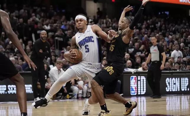 Orlando Magic forward Paolo Banchero (5) drives around Cleveland Cavaliers forward Isaac Okoro, right, in the second half of Game 7 of an NBA basketball first-round playoff series, Sunday, May 5, 2024, in Cleveland. (AP Photo/Sue Ogrocki)
