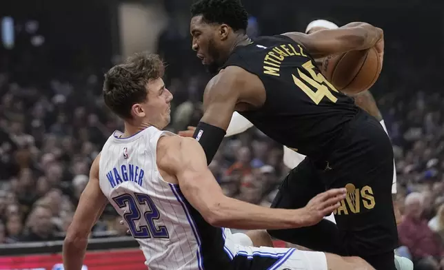 Orlando Magic forward Franz Wagner (22) fouls Cleveland Cavaliers guard Donovan Mitchell (45) and falls to the floor in the first half of Game 7 of an NBA basketball first-round playoff series Sunday, May 5, 2024, in Cleveland. (AP Photo/Sue Ogrocki)