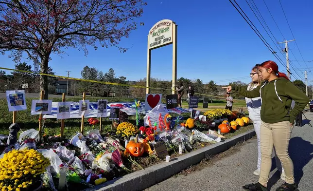 FILE - Community members look at a memorial outside Schemengees Bar &amp; Grille about one week after a mass shooting, Nov. 3, 2023, in Lewiston, Maine. An independent commission investigating the mass shooting that left 18 people dead in Maine is scheduled to hear from the family of the shooter, Robert Card, for the first time on Thursday, May 15, 2024. (AP Photo/Matt York, File)