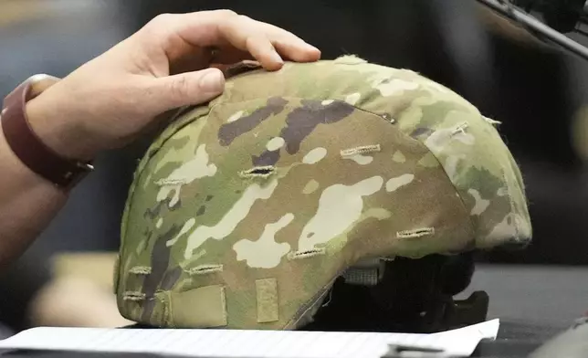 Nicole Herling, sister of shooter Robert Card, rests her hand on her brother's military helmet, while testifying, Thursday, May 16, 2024, in Augusta, Maine, during a hearing of the independent commission investigating the law enforcement response to the mass shooting in Lewiston, Maine. (AP Photo/Robert F. Bukaty)