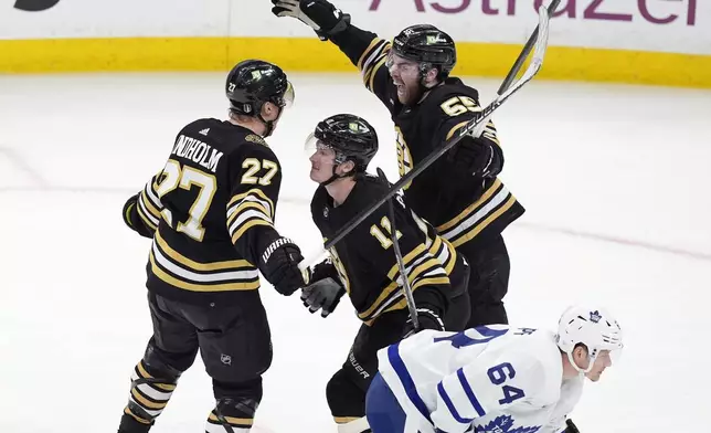 Boston Bruins' Hampus Lindholm (27) celebrates his goal with Justin Brazeau (55) and Trent Frederic (11) behind Toronto Maple Leafs' David Kampf (64) during the third period of Game 7 of an NHL hockey Stanley Cup first-round playoff series, Saturday, May 4, 2024, in Boston. (AP Photo/Michael Dwyer)