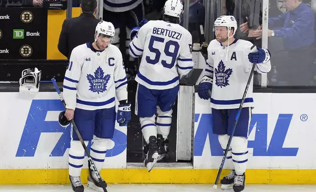 Toronto Maple Leafs' Tyler Bertuzzi (59) leaves the ice between John Tavares (91) and Morgan Rielly (44) after the team lost to the Boston Bruins in overtime during Game 7 of an NHL hockey Stanley Cup first-round playoff series, Saturday, May 4, 2024, in Boston. (AP Photo/Michael Dwyer)