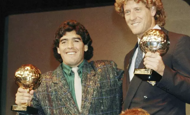 FILE - Argentina's soccer star Diego Maradona, left, and West German goalkeeper Harald Schumacher are holding their World Cup Soccer Ball awards while posing with two young soccer players during the Soccer Golden Shoe Award ceremony held in Paris, France, on Nov. 13, 1986. Diego Maradona's heirs filed a lawsuit to try to stop the auction of a trophy he was awarded after the 1986 World Cup won by Argentina. (AP Photo/Michael Lipchitz, File)