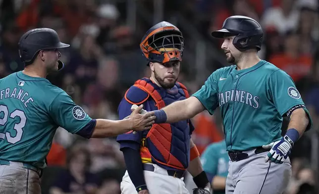 Seattle Mariners' Cal Raleigh, right, is congratulated by Ty France, left, as Houston Astros catcher Victor Caratini, center, looks on after hitting a two-run home run during the sixth inning of a baseball game Saturday, May 4, 2024, in Houston. (AP Photo/Kevin M. Cox)