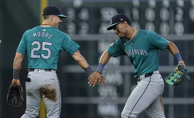 Seattle Mariners shortstop Dylan Moore (25) celebrates with center fielder Julio Rodríguez, right, after a baseball game against the Houston Astros, Saturday, May 4, 2024, in Houston. (AP Photo/Kevin M. Cox)