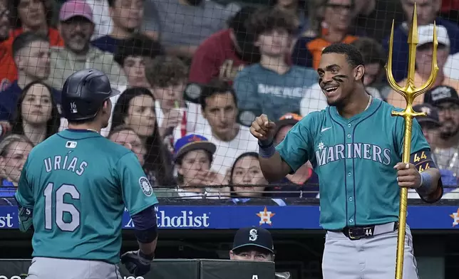 Seattle Mariners' Luis Urías (16) is presented with a trident by Julio Rodríguez after hitting a solo home run during the fifth inning of a baseball game against the Houston Astros Saturday, May 4, 2024, in Houston. (AP Photo/Kevin M. Cox)
