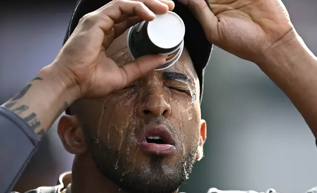 Washington Nationals' Eddie Rosario cools off with water in the dugout during the sixth inning of a baseball game against the Seattle Mariners, Saturday, May 25, 2024, in Washington. (AP Photo/John McDonnell)