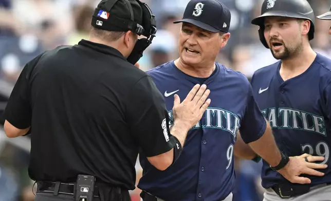 Home plate umpire Dan Bellino, left, talks with Seattle Mariners manager Scott Servais, center, about a called third strike on Cal Raleigh, right, during the ninth inning of the team's baseball game against the Washington Nationals, Saturday, May 25, 2024, in Washington. Servais was later ejected. (AP Photo/John McDonnell)