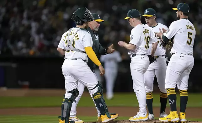 Oakland Athletics pitcher JP Sears (38) hands the ball over to manager Mark Kotsay, second from left, as he exits during the seventh inning of a baseball game against the Miami Marlins, Friday, May 3, 2024, in Oakland, Calif. (AP Photo/Godofredo A. Vásquez)