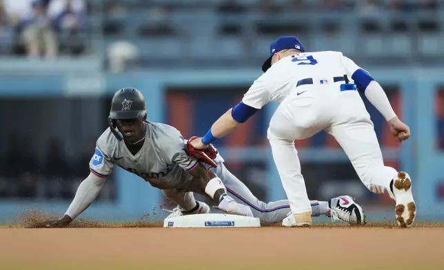 Miami Marlins' Jazz Chisholm Jr., left, steals second base ahead of a tag by Los Angeles Dodgers second baseman Gavin Lux (9) during the first inning of a baseball game in Los Angeles, Monday, May 6, 2024. (AP Photo/Ashley Landis)