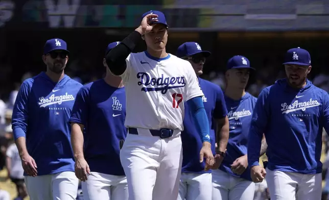 Los Angeles Dodgers designated hitter Shohei Ohtani, center, walks back to the dugout with teammates after the Dodgers defeated the Miami Marlins 3-1 in a baseball game Wednesday, May 8, 2024, in Los Angeles. (AP Photo/Mark J. Terrill)
