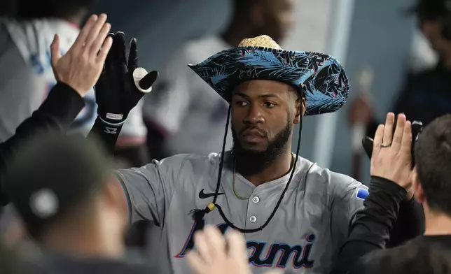 Miami Marlins' Bryan De La Cruz celebrates with teammates in the dugout after his solo home run against the Los Angeles Dodgers during the sixth inning of a baseball game Tuesday, May 7, 2024, in Los Angeles. (AP Photo/Marcio Jose Sanchez)