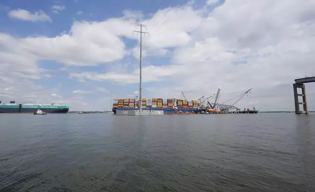 A vessel, left, moves past the stranded container ship Dali, through a newly opened deep-water channel in Baltimore after being stuck in the harbor since the Francis Scott Key Bridge collapsed four weeks ago, Thursday, April 25, 2024. (AP Photo/Matt Rourke)