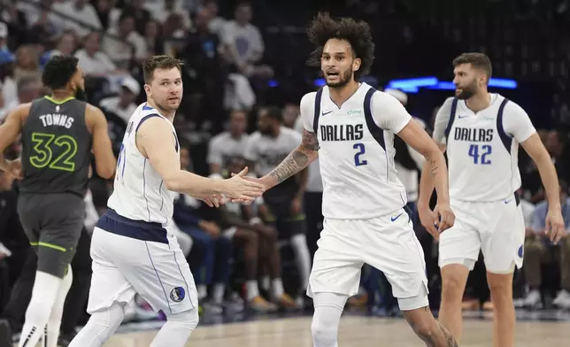 Dallas Mavericks center Dereck Lively II (2) slaps hands with Mavericks guard Luka Doncic, second from left, after Doncic's score against the Minnesota Timberwolves during the first half of Game 5 of the Western Conference finals in the NBA basketball playoffs, Thursday, May 30, 2024, in Minneapolis. (AP Photo/Abbie Parr)