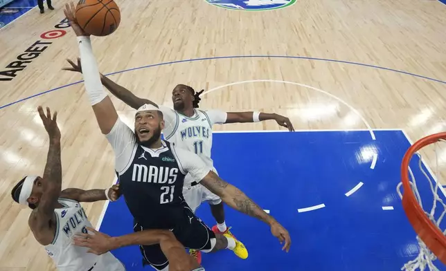 Dallas Mavericks center Daniel Gafford (21) reaches for a rebound against Minnesota Timberwolves guard Nickeil Alexander-Walker, left, and center Naz Reid (11) during the first half of Game 1 of the NBA basketball Western Conference finals, Wednesday, May 22, 2024, in Minneapolis. (AP Photo/Abbie Parr)