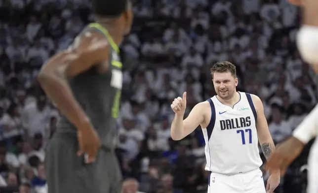 Dallas Mavericks guard Luka Doncic (77) celebrates his score as Minnesota Timberwolves guard Anthony Edwards, left, looks on during the first half of Game 5 of the Western Conference finals in the NBA basketball playoffs, Thursday, May 30, 2024, in Minneapolis. (AP Photo/Abbie Parr)