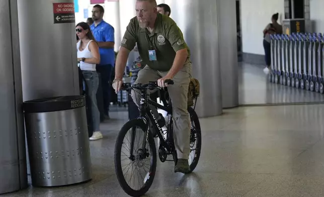 A member of the U.S. Department of Homeland Security patrols at Miami International Airport, Thursday, May 23, 2024, in Miami. A record number of Americans are expected to travel over the 2024 Memorial Day holiday. (AP Photo/Lynne Sladky)