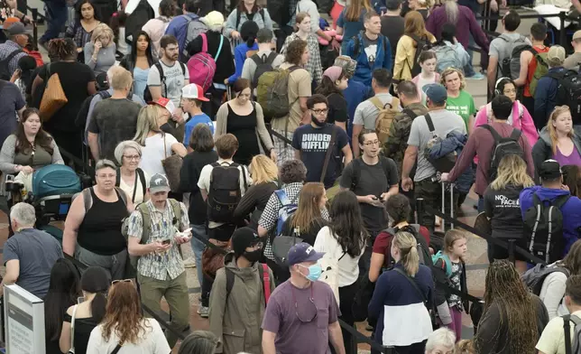 FILE - Travelers move through a security checkpoint in Denver International Airport ahead of the Memorial Day holiday on May 26, 2023, in Denver. A record number of Americans are expected to hit the pavement and the air over the 2024 Memorial Day weekend. (AP Photo/David Zalubowski, File)